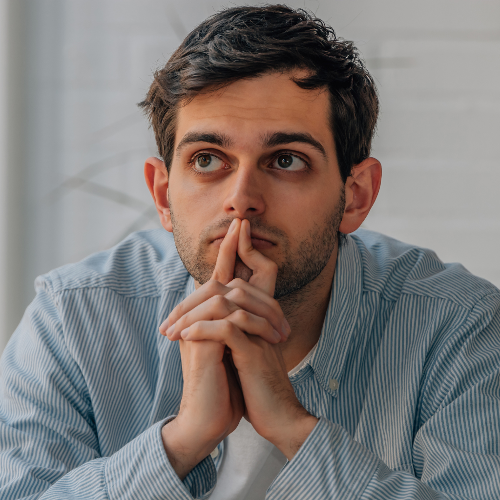 OCD Coping Strategies: Practical Approaches for Everyday Life 1 Man sitting quietly with hands clasped, reflecting intrusive thoughts often experienced with OCD.