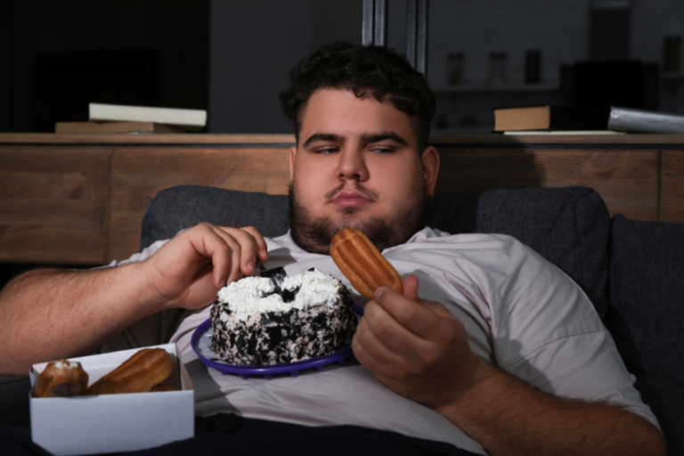 Man experiencing depression-related appetite changes while eating comfort food on a couch