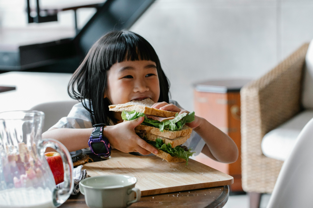 Child eating a large sandwich, representing binge eating patterns in children