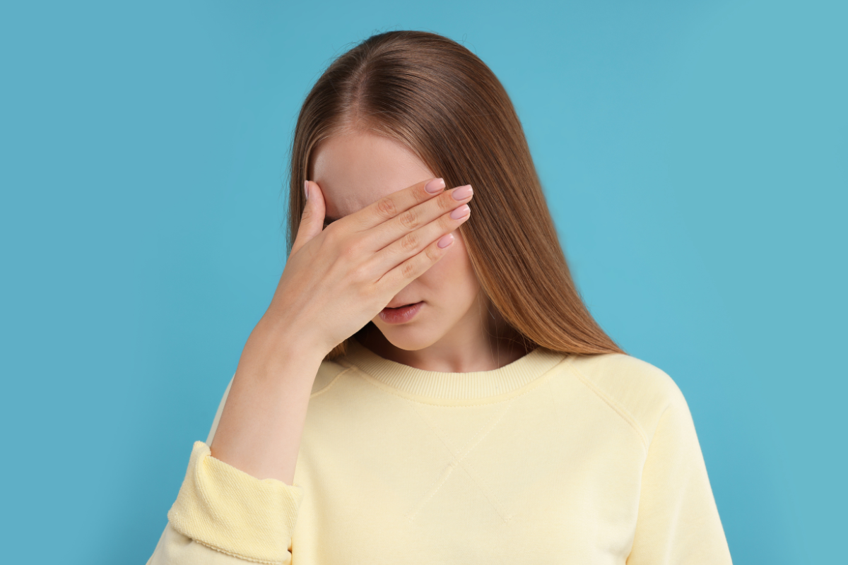 Woman covering her face, representing emotional exhaustion and the hidden effort of ADHD masking