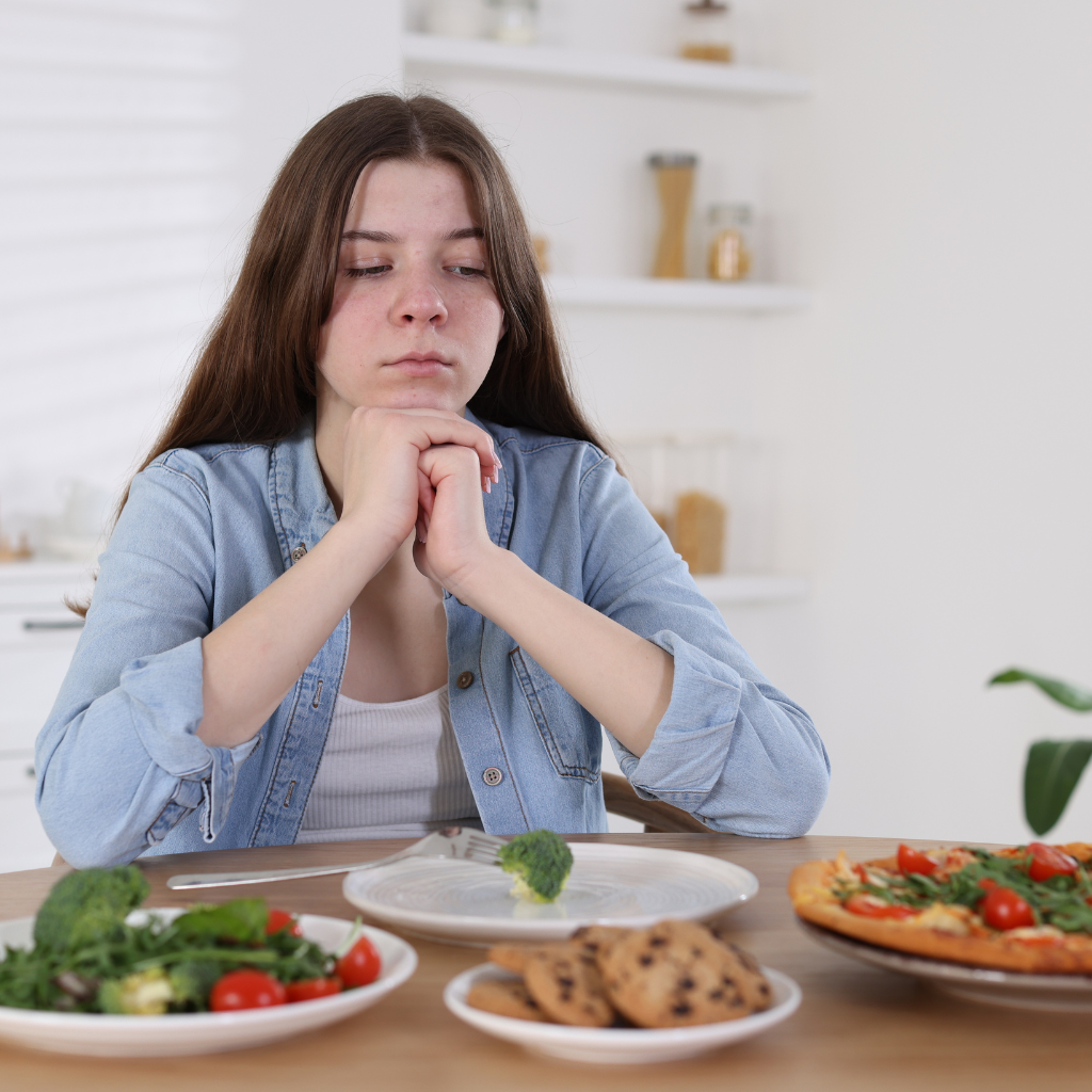 teen girl avoiding food at mealtime, representing restrictive eating patterns in eating disorders