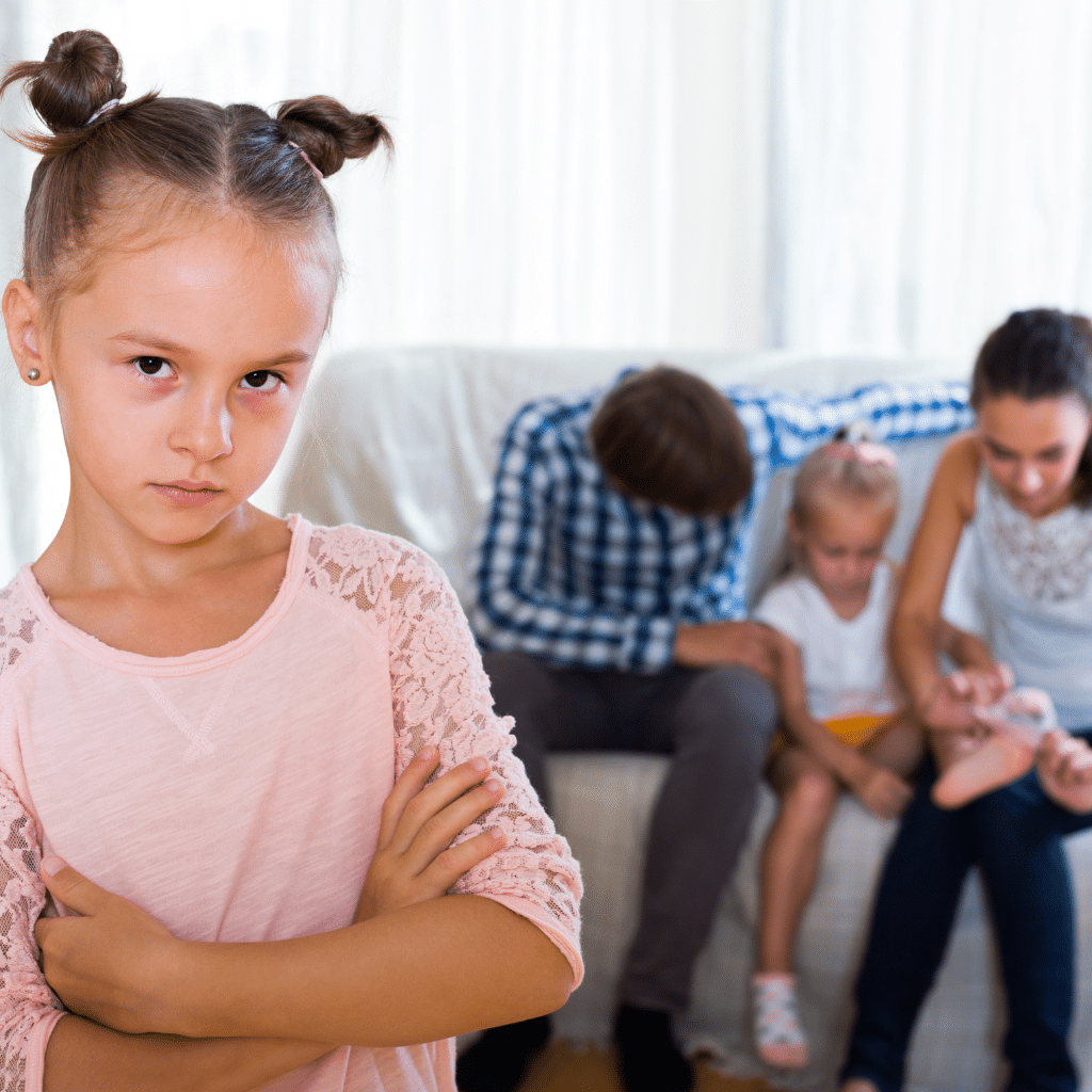 Supporting Siblings of PTSD Children: Addressing Their Needs 1 Sibling standing apart while parents focus on a child with PTSD