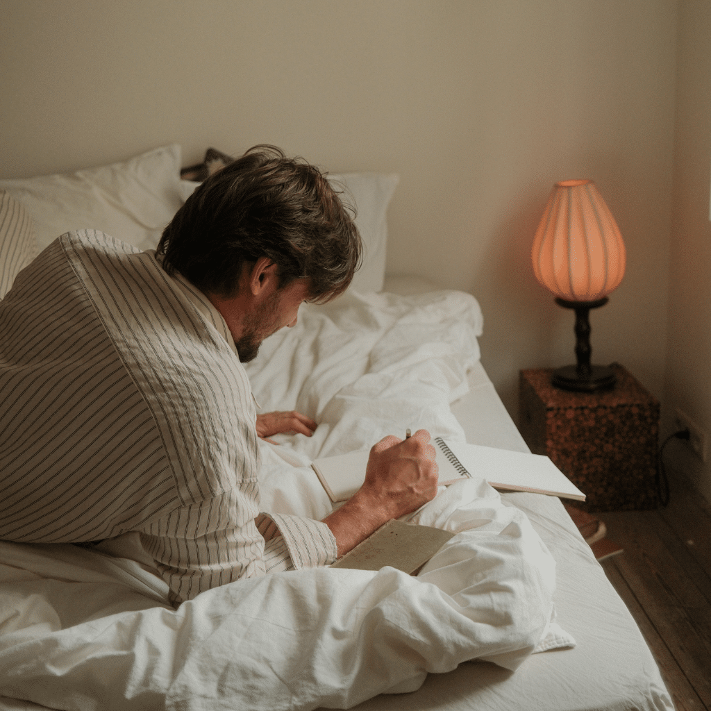 Person journaling in bed as part of an evening wind down routine