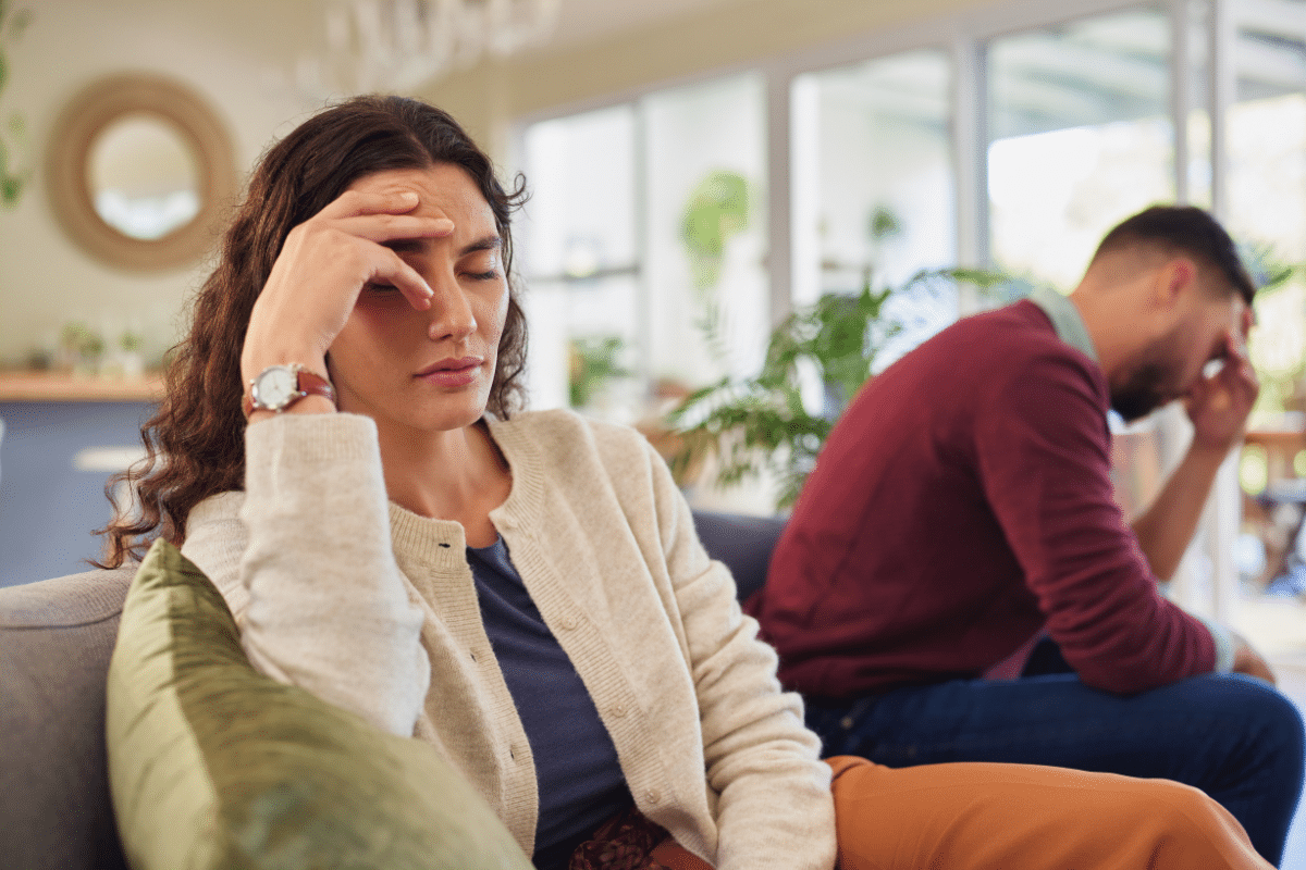 Couple sitting apart and appearing emotionally distressed, representing how ADHD can affect communication and connection in relationships.