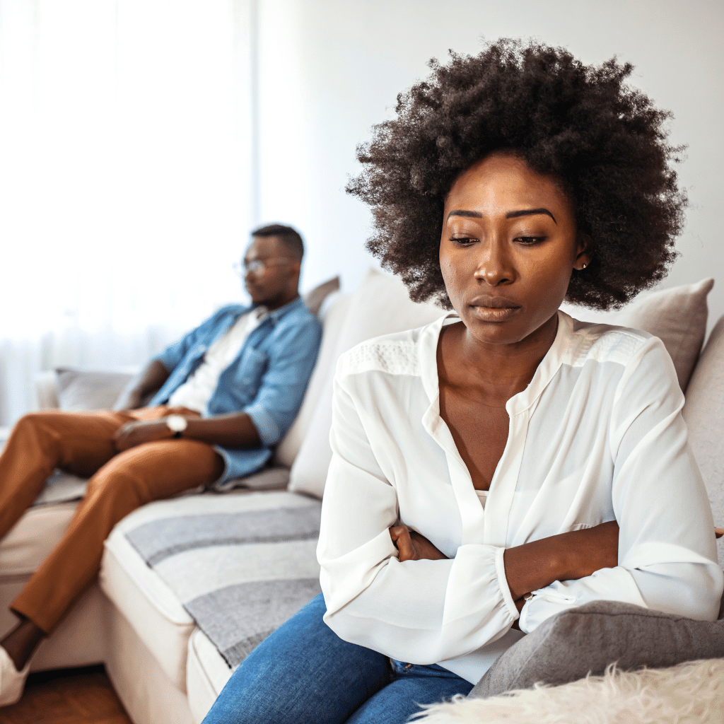 Partner looking concerned while the other sits apart, symbolizing strain in adult relationships affected by ADHD symptoms.