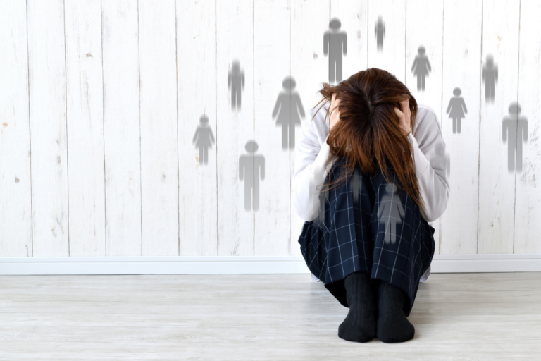Person sitting on the floor with head in hands, symbolizing emotional distress linked to PTSD and depression