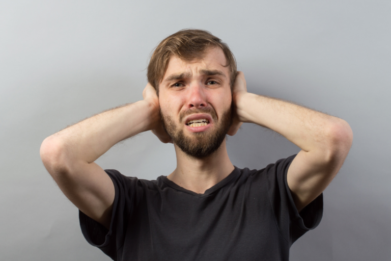 Man covering his ears during PTSD sensory overload.