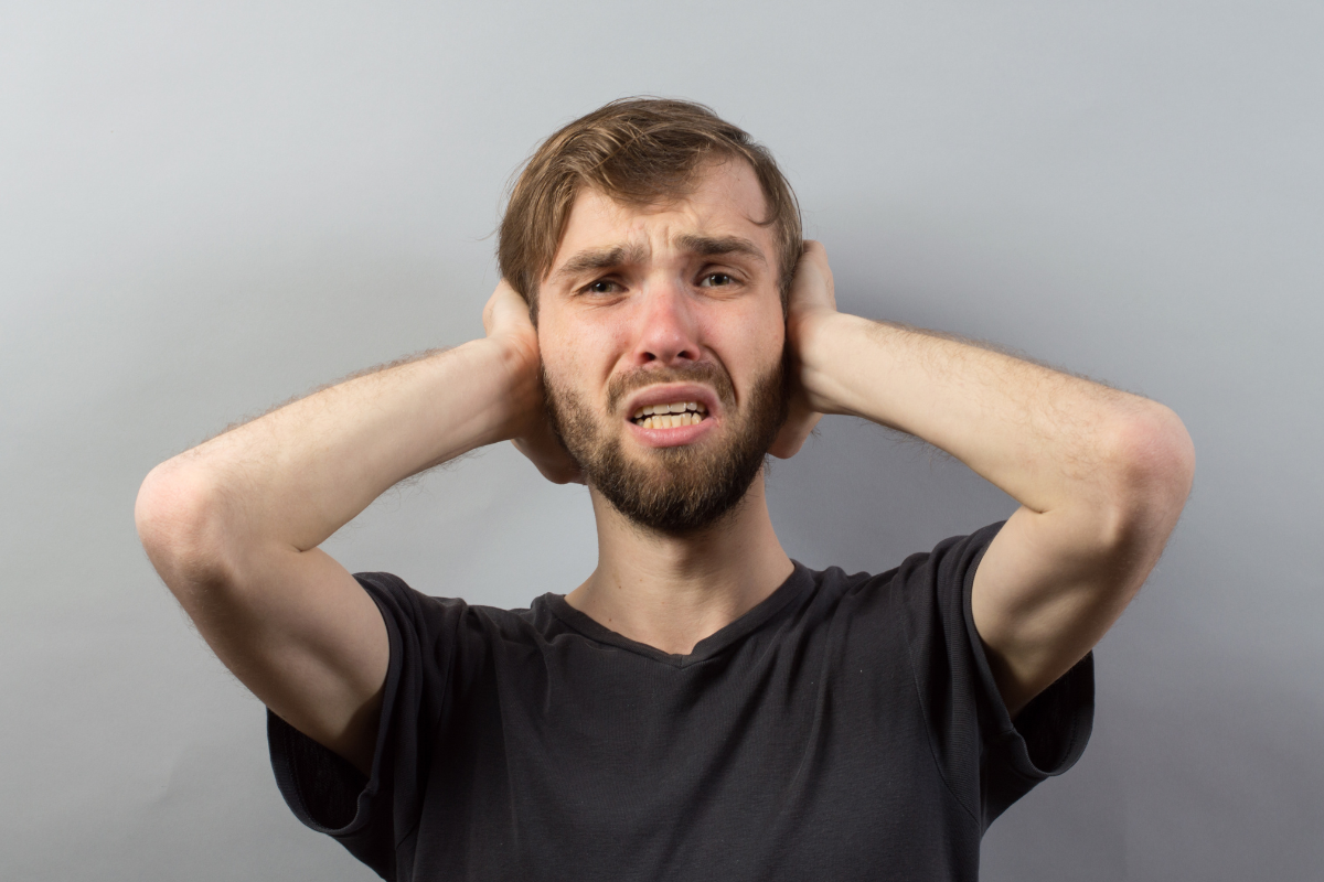 Man covering his ears during PTSD sensory overload.