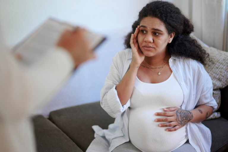 Pregnant woman showing signs of anxiety during pregnancy during a medical consultation.