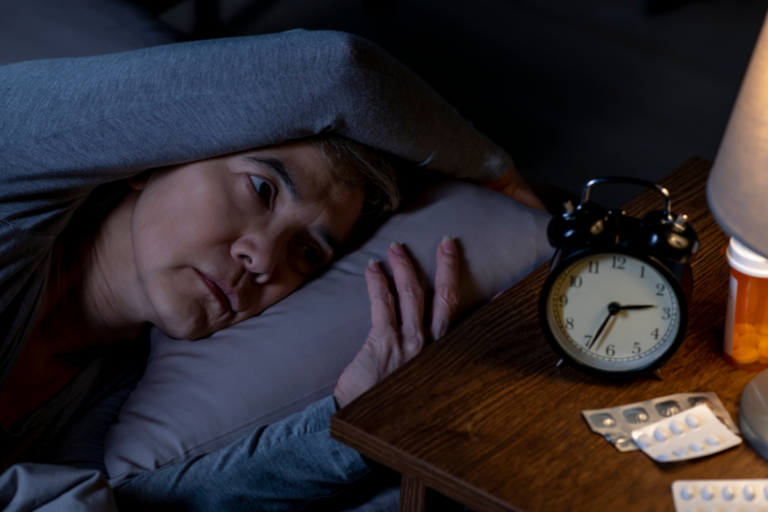 Person awake at night with insomnia, looking at the clock.