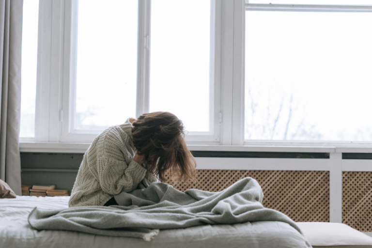 A woman on her bed, emotionally overwhelmed suffering from depression relapse.