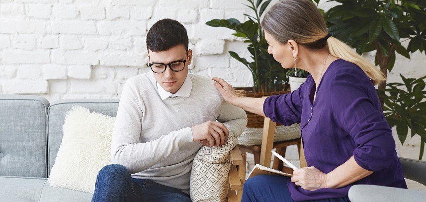 candid shot casually dressed professional woman psychotherapist her fifties touching her young male patient by shoulder while having counseling session expressing sympathy support 1 1 1