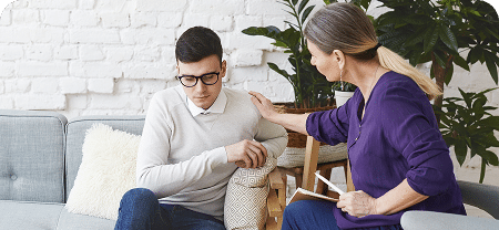 candid shot casually dressed professional woman psychotherapist her fifties touching her young male patient by shoulder while having counseling session expressing sympathy support 1