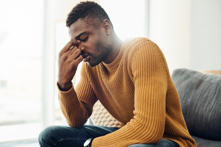 Man sitting with head in hand, showing emotional exhaustion and symptoms of burnout or depression