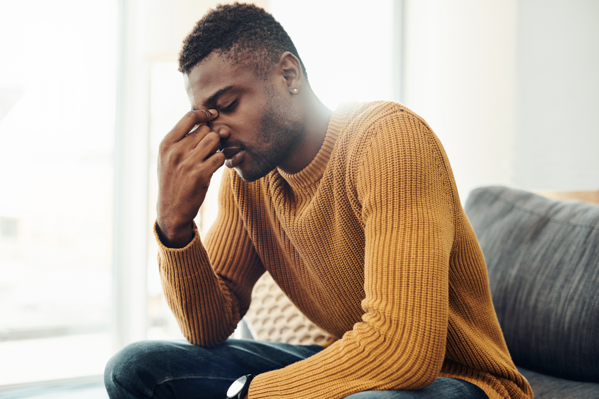 Man sitting with head in hand, showing emotional exhaustion and symptoms of burnout or depression