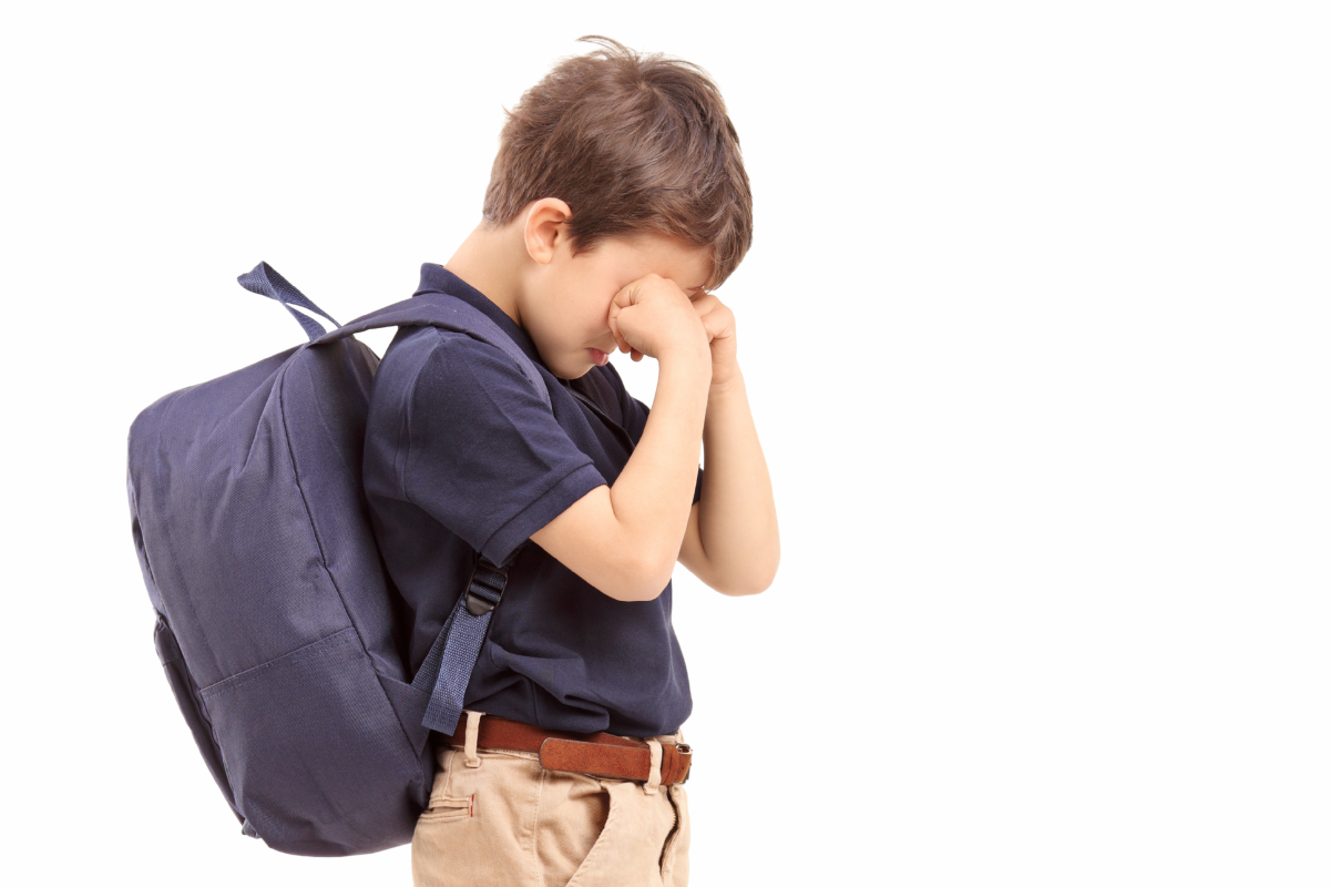 Child with backpack showing distress and anxiety about going to school