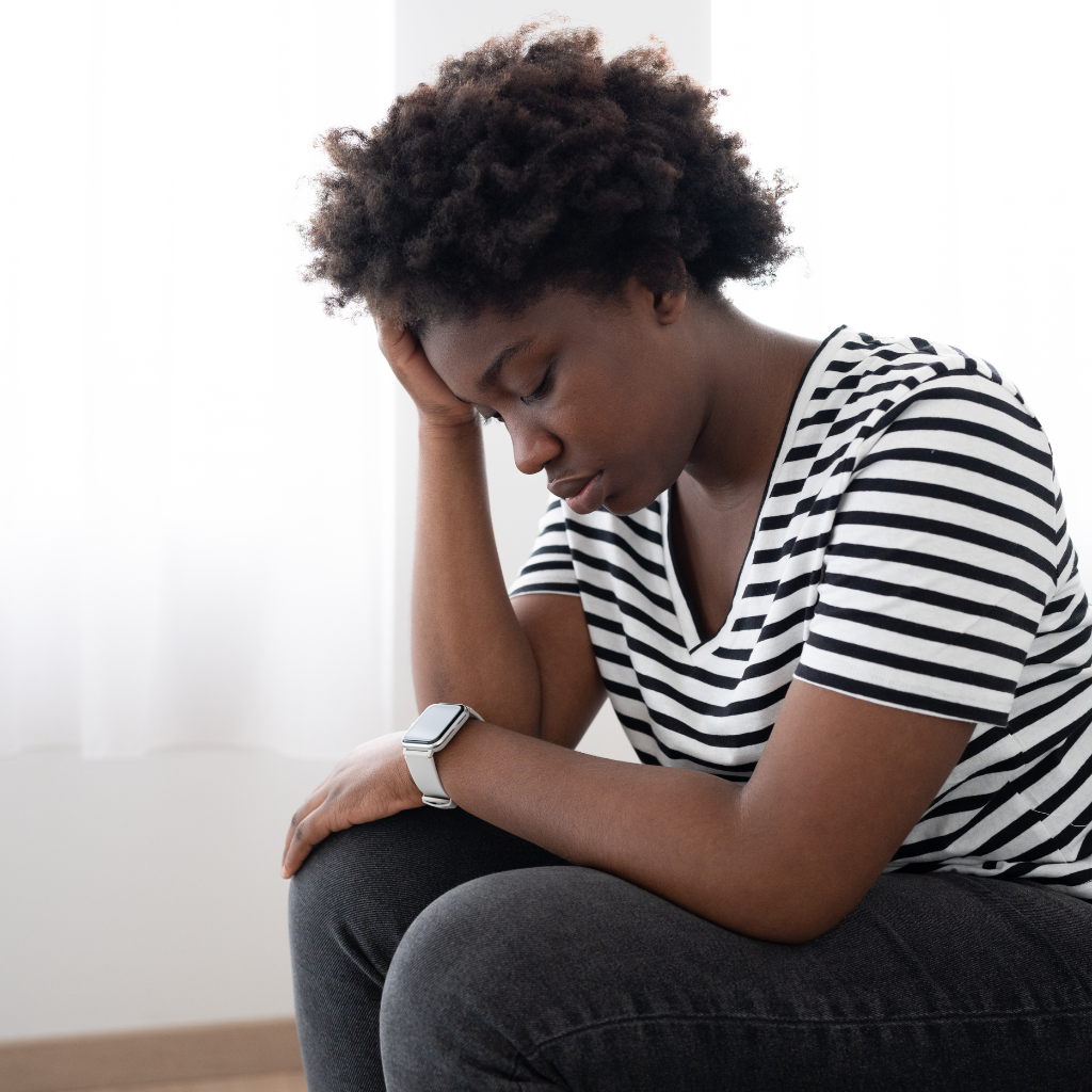 Woman sitting with her head in her hand, reflecting the emotional distress associated with anxiety and PTSD.