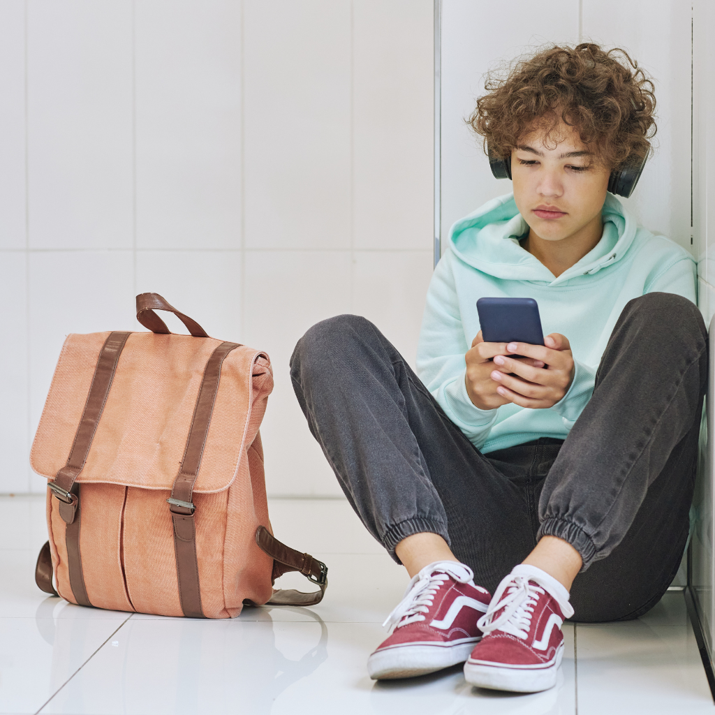 Kid showing signs of school refusal anxiety while sitting alone with a backpack before school.
