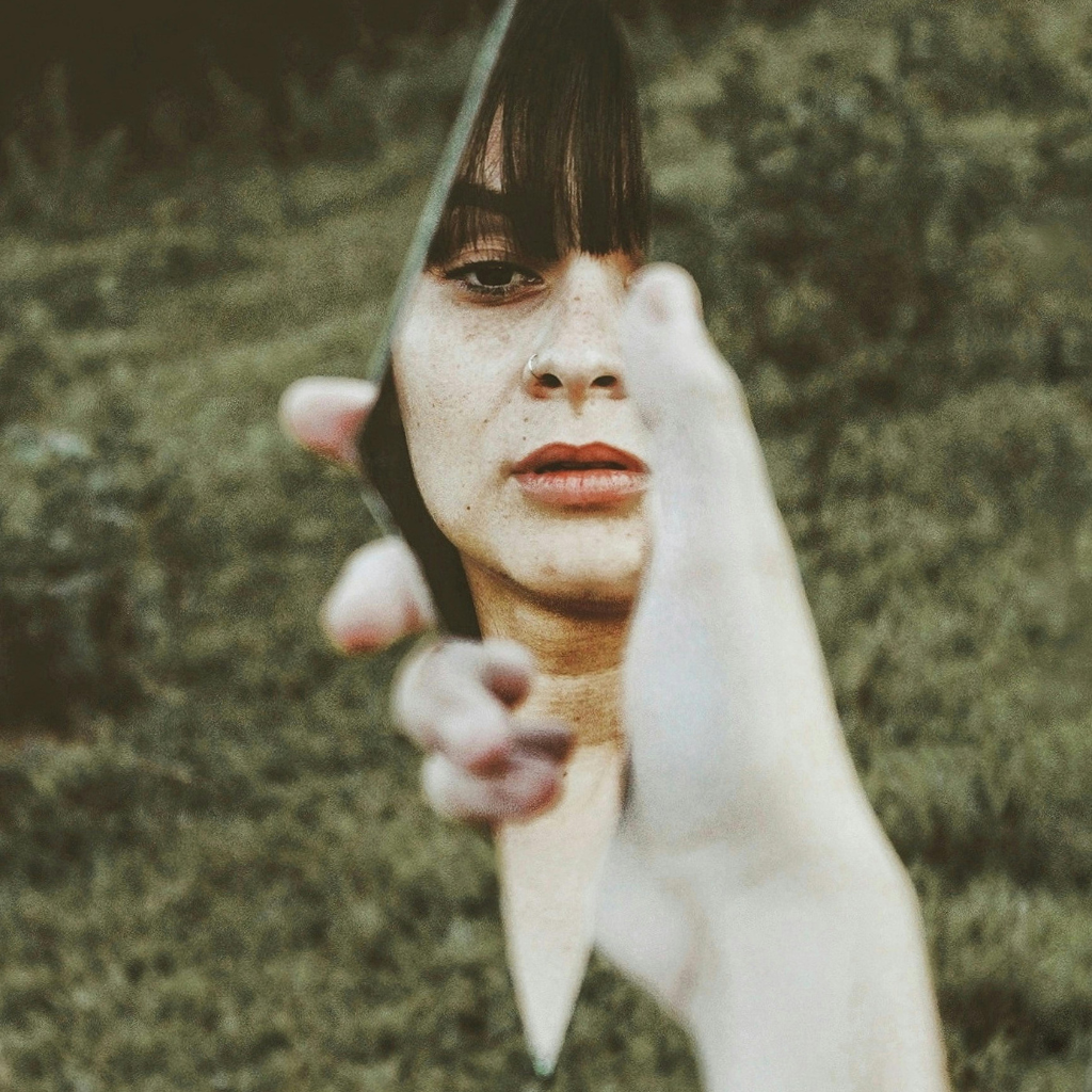 Woman looking into a mirror while confronting distressing intrusive thoughts, illustrating the fear and anxiety associated with harm OCD.