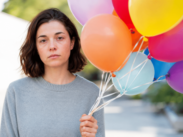 woman holding balloons for a birthday party with blank expression and feels nothing