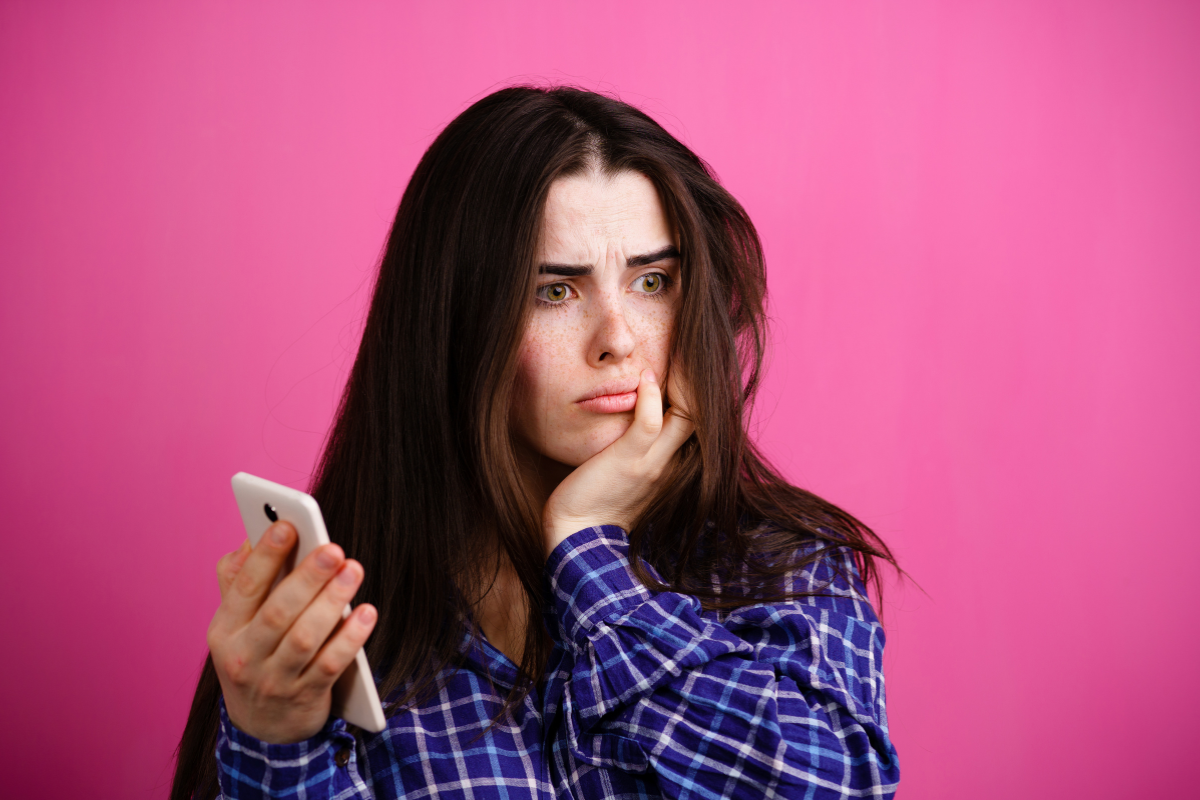 Woman holding a phone with a worried expression, reflecting phone anxiety before making or answering a call.