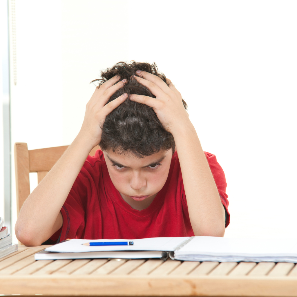Child struggling with homework at a table, showing why ADHD homework help may be needed.