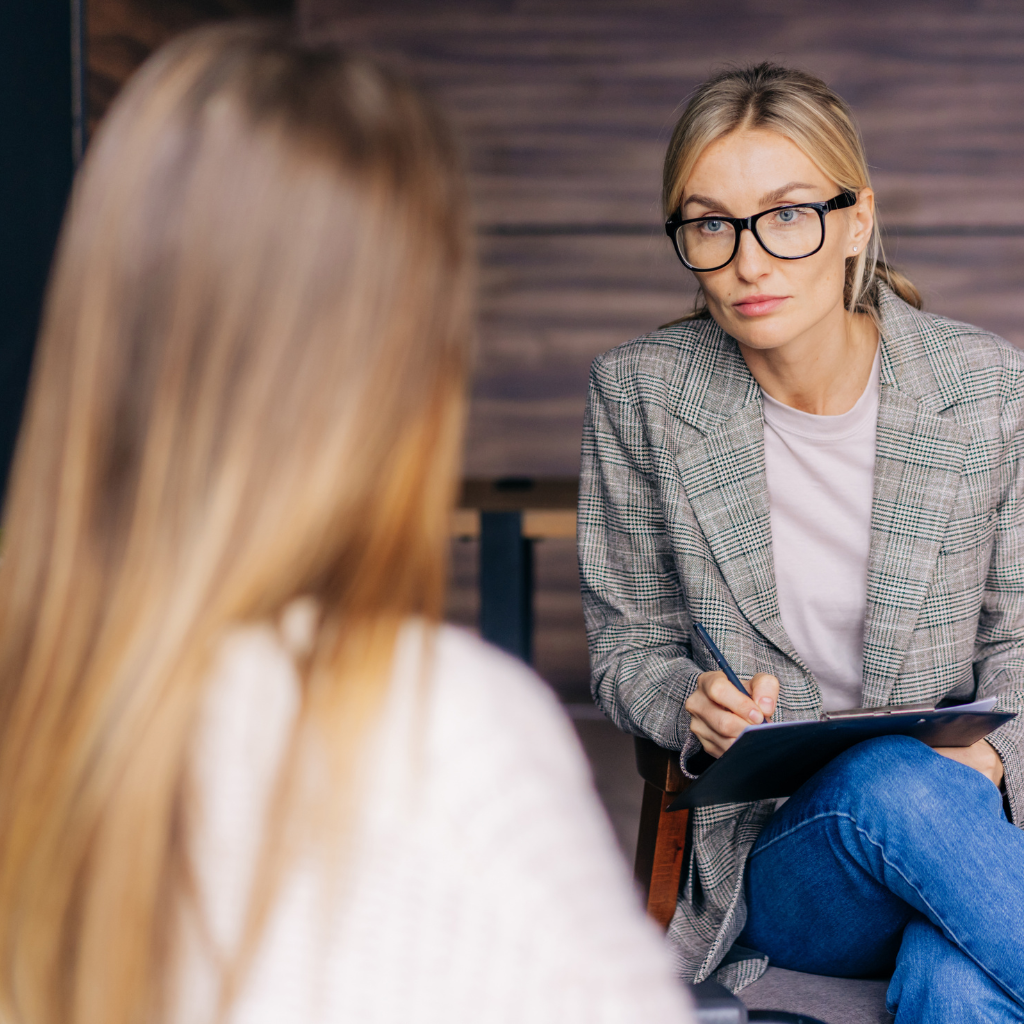 Therapist taking notes during a counseling session about health anxiety, symptom checking, and treatment options.