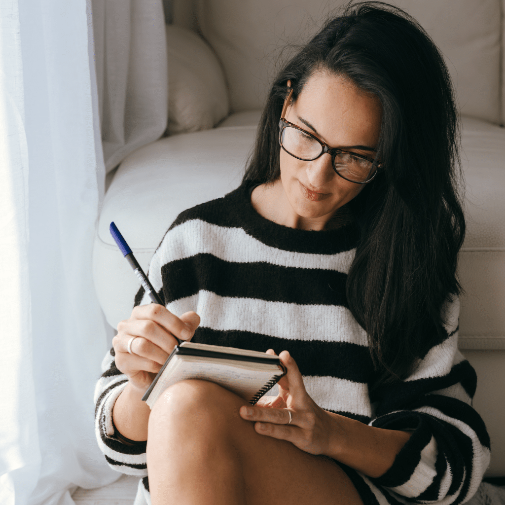 Woman writing in a journal to track mood, sleep, and cycle changes related to bipolar disorder and hormones.