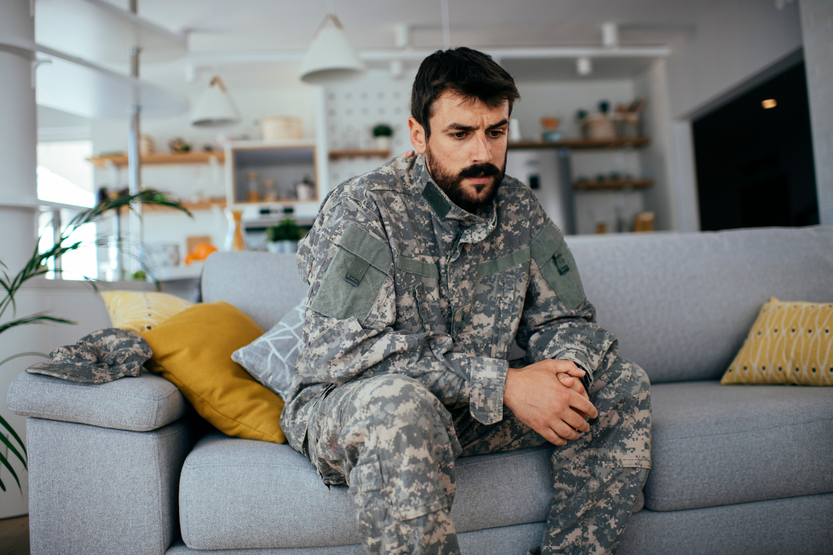 Veteran sitting tensely at home, reflecting hypervigilance and feeling under threat after PTSD.