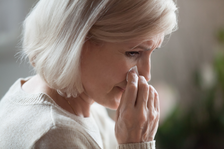 Woman wiping away tears, reflecting the pain of grief and the difficulty of recognizing when support may help.