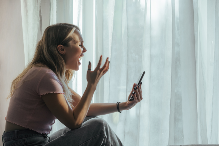 Woman reacting intensely to a phone message, illustrating how emotional dysregulation in BPD can feel sudden and overwhelming.