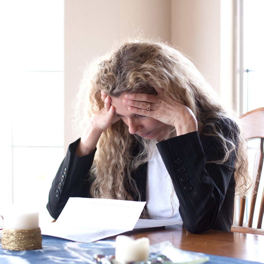Woman holding her head over papers, showing how worry can feel difficult to control when it becomes part of an anxiety disorder.