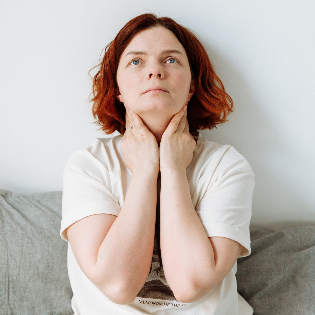 Catastrophizing and Anxiety: Why You Always Expect the Worst 1 Woman holding her throat and looking worried, showing how catastrophizing anxiety can turn a small body sensation into a worst-case fear.