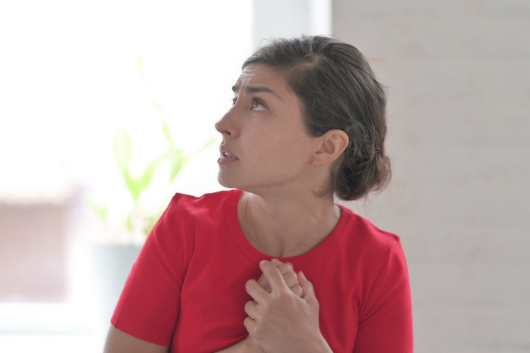 Animo Sano Psychiatry 41 Woman looking tense and holding her chest, showing how performance anxiety at work can feel physically overwhelming.