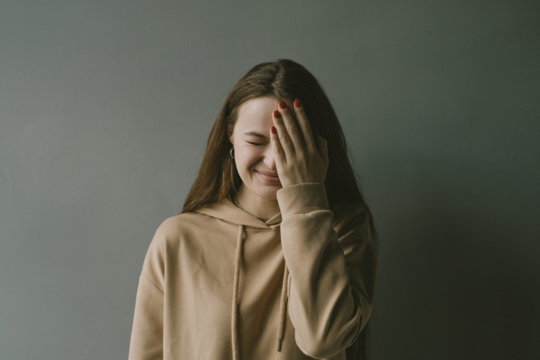 Smiling woman covering face with hand