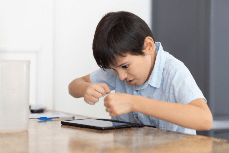 Child intensely focused on a tablet, reflecting how ADHD signs in children can include impulsivity, distraction, or trouble shifting attention.