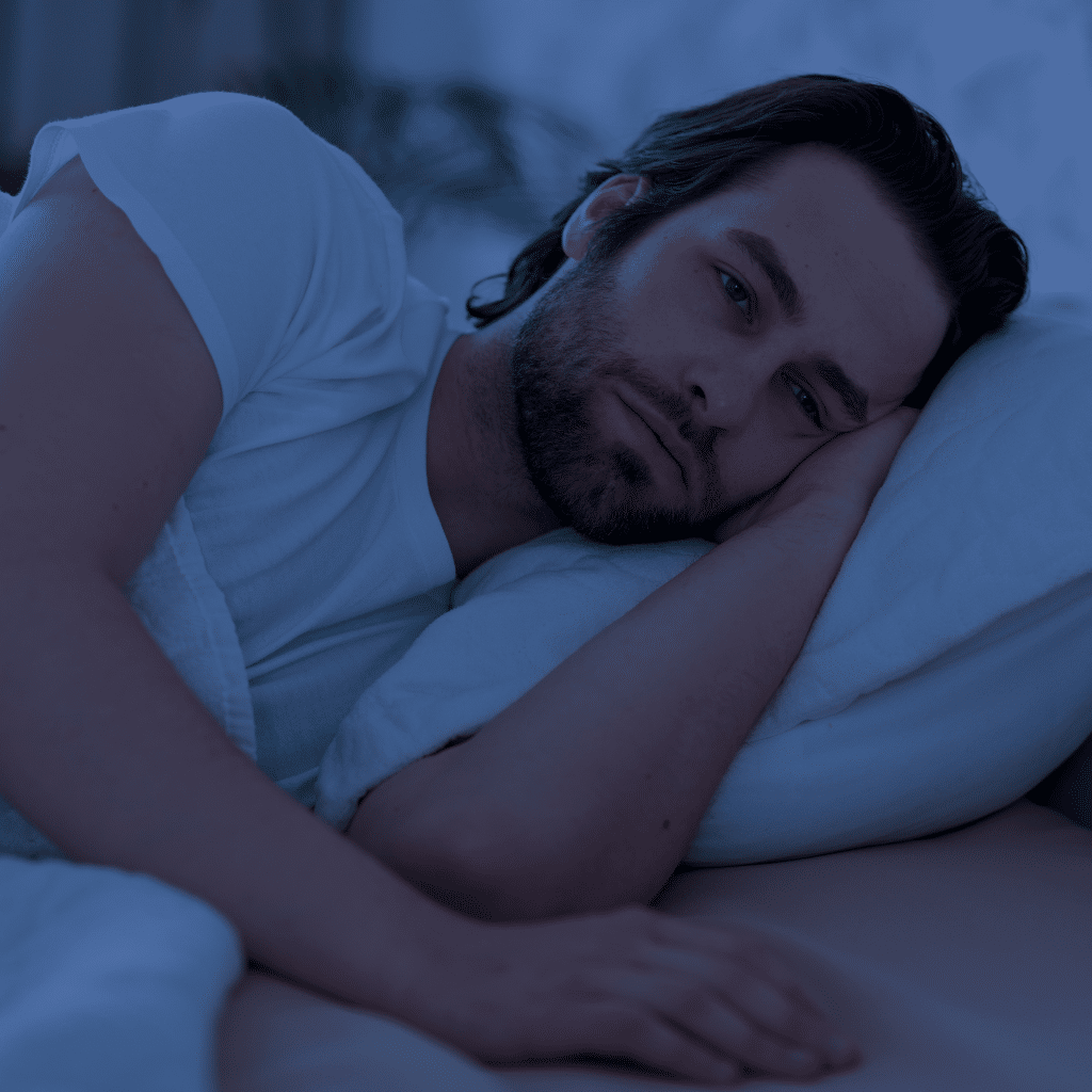 Man lying awake in bed at night, reflecting how some men keep difficult thoughts and emotions to themselves instead of talking about them.