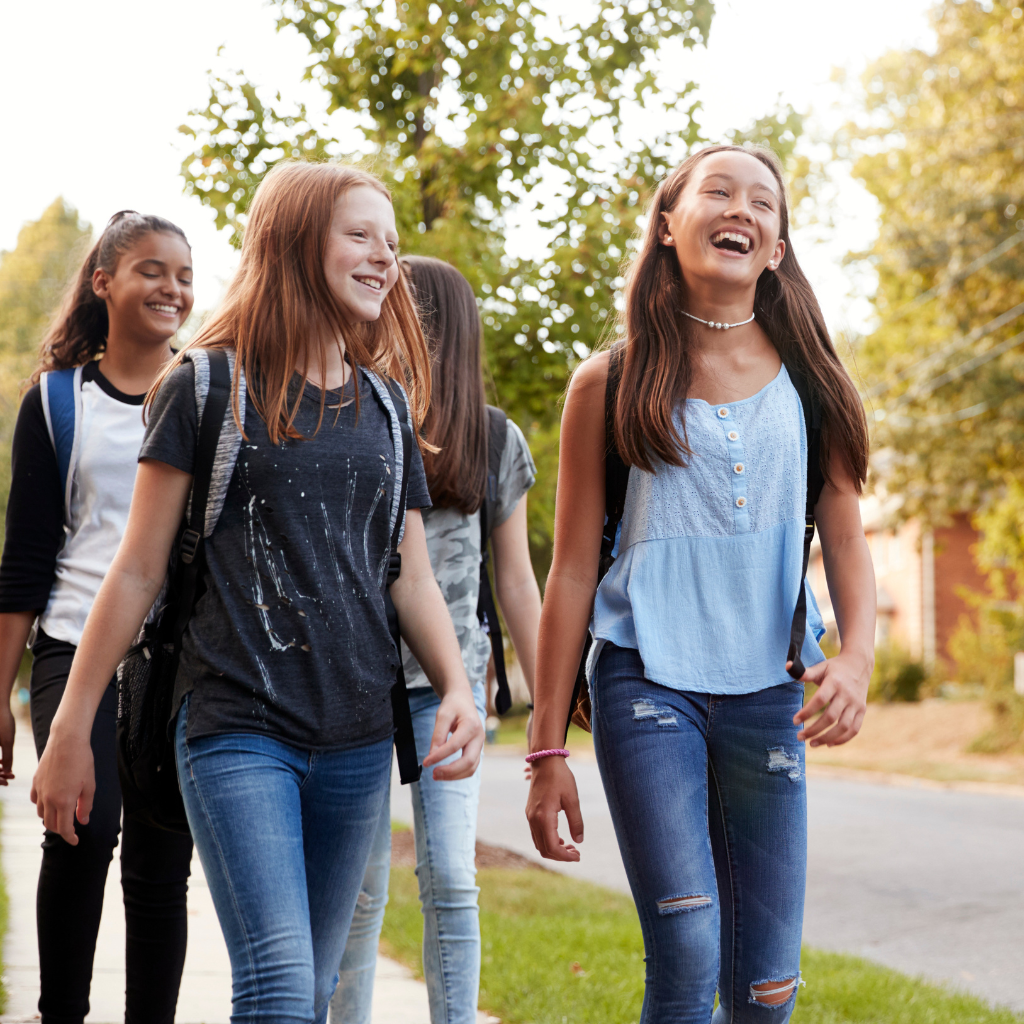Group of teens walking and laughing together outdoors, showing friendship and connection away from social media.