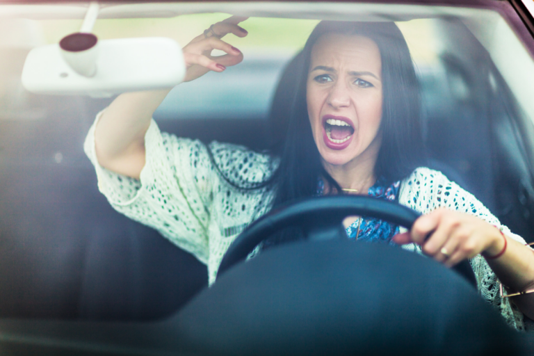 Woman shouting in frustration while driving, reflecting an intense anger response.