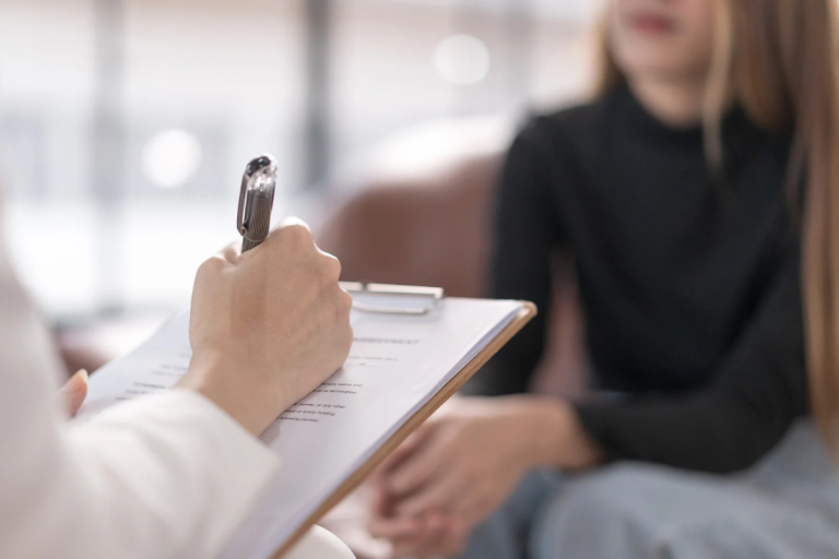 Therapist taking notes while speaking with a patient during an initial therapy consultation.