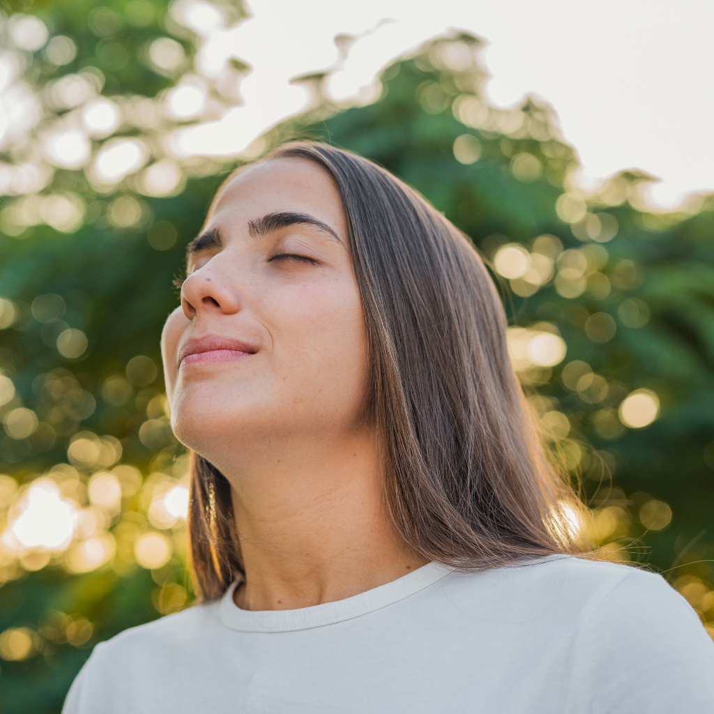 Woman practicing mindful breathing outdoors, illustrating a calming strategy that can support emotional regulation.