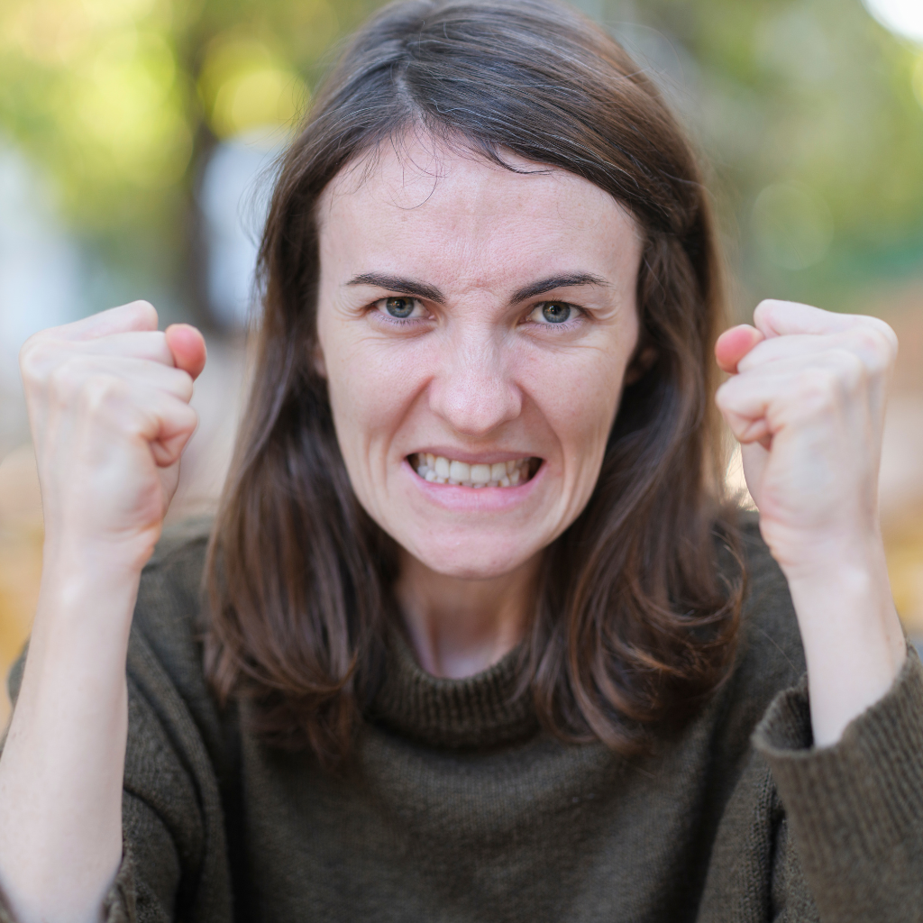 Woman clenching her fists with an intense expression, showing the fast, strong emotional reactions associated with ADHD emotional dysregulation.