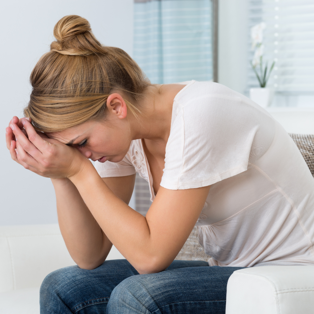 Military spouse sitting with her head in her hands, appearing overwhelmed by ongoing stress and responsibilities.